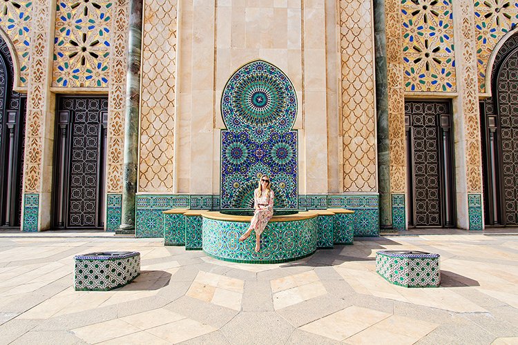 Woman standing at an ornate mosaic fountain at Hassan II Mosque in Casablanca, Morocco