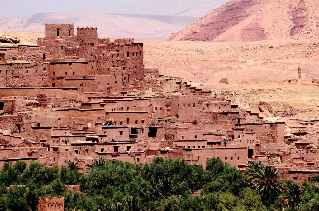 Sunset view of Aït Benhaddou, an ancient ksar near Ouarzazate, Morocco with traditional mudbrick architecture and palm trees