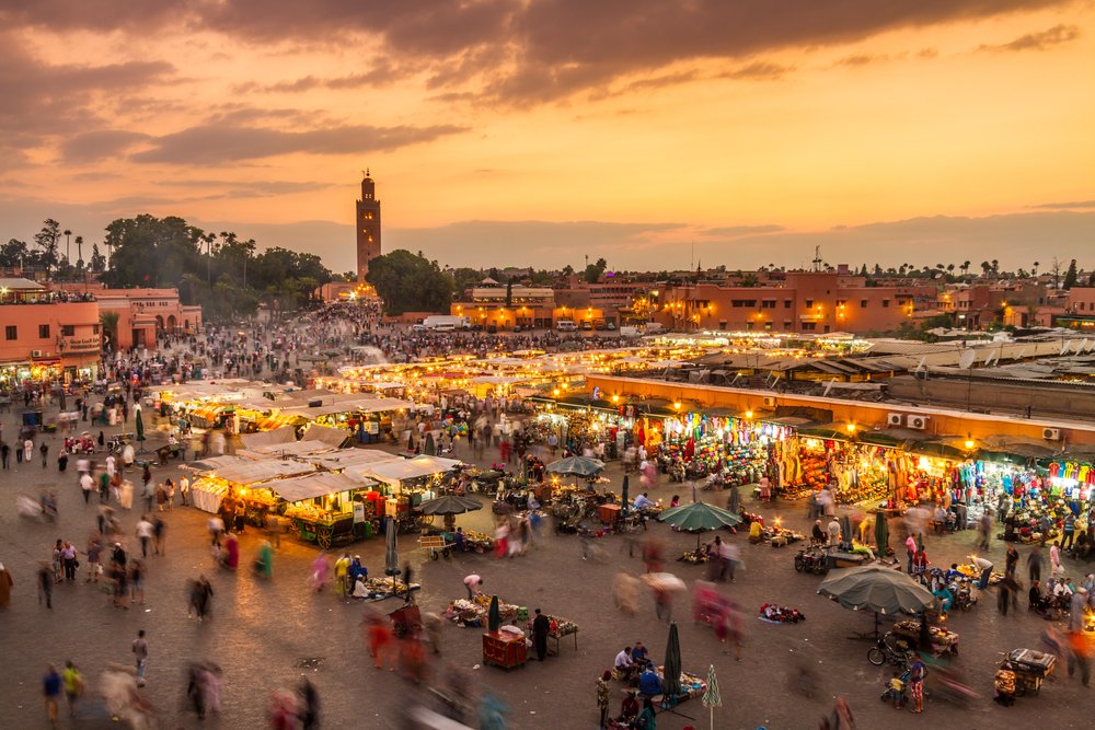 Evening view of Jemaa el-Fna square in Marrakech, Morocco with market stalls, food vendors, and the Koutoubia Mosque in the background