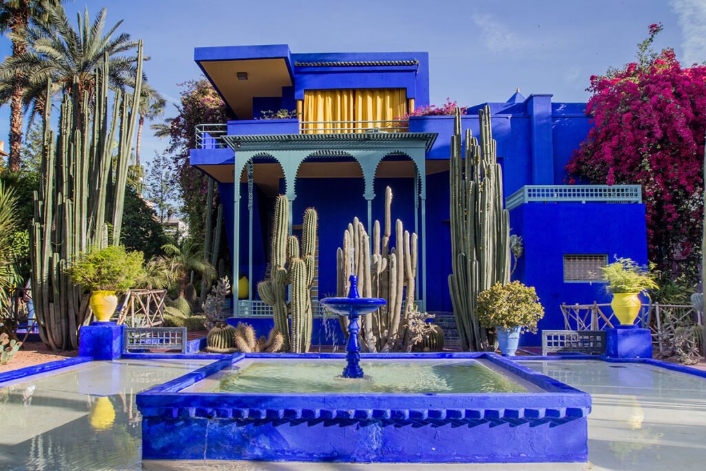 Bright blue villa and cactus garden at Jardin Majorelle in Marrakech, Morocco with fountain in the foreground